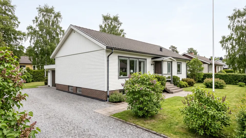Vit enplansvilla från 1970-talet med trädgård och grusuppfart